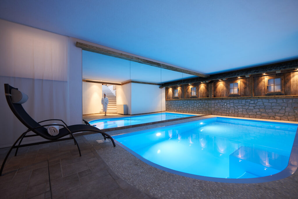 Blick auf den Pool mit Spiegelwand für eine größere Raumwirkung und Liegestuhl