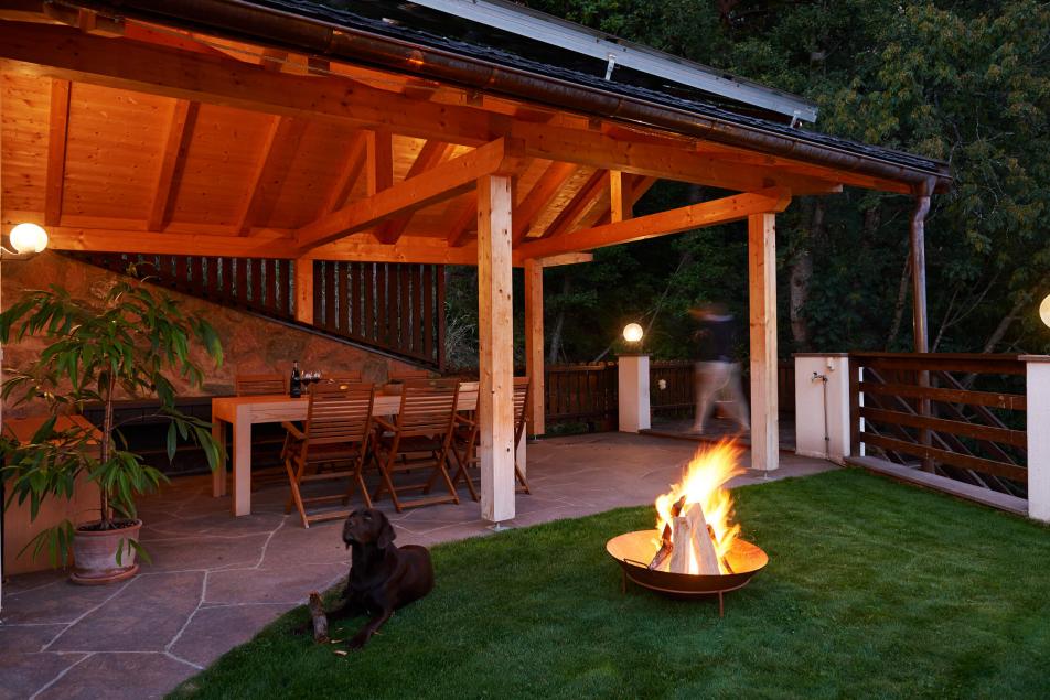 Gemütliche überdachte Sitzecke mit Feuerschale und Hund auf Wiese im Chalet Südtirol